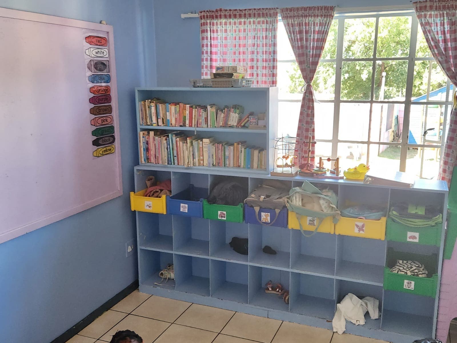 A Tiny Town classroom reading corner with a bookshelf and labelled cubby storage