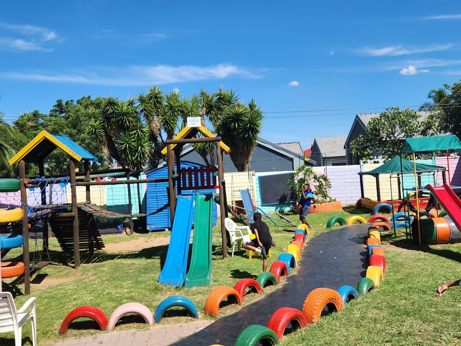Children playing on the slides and painted tyre path in the Tiny Town playground