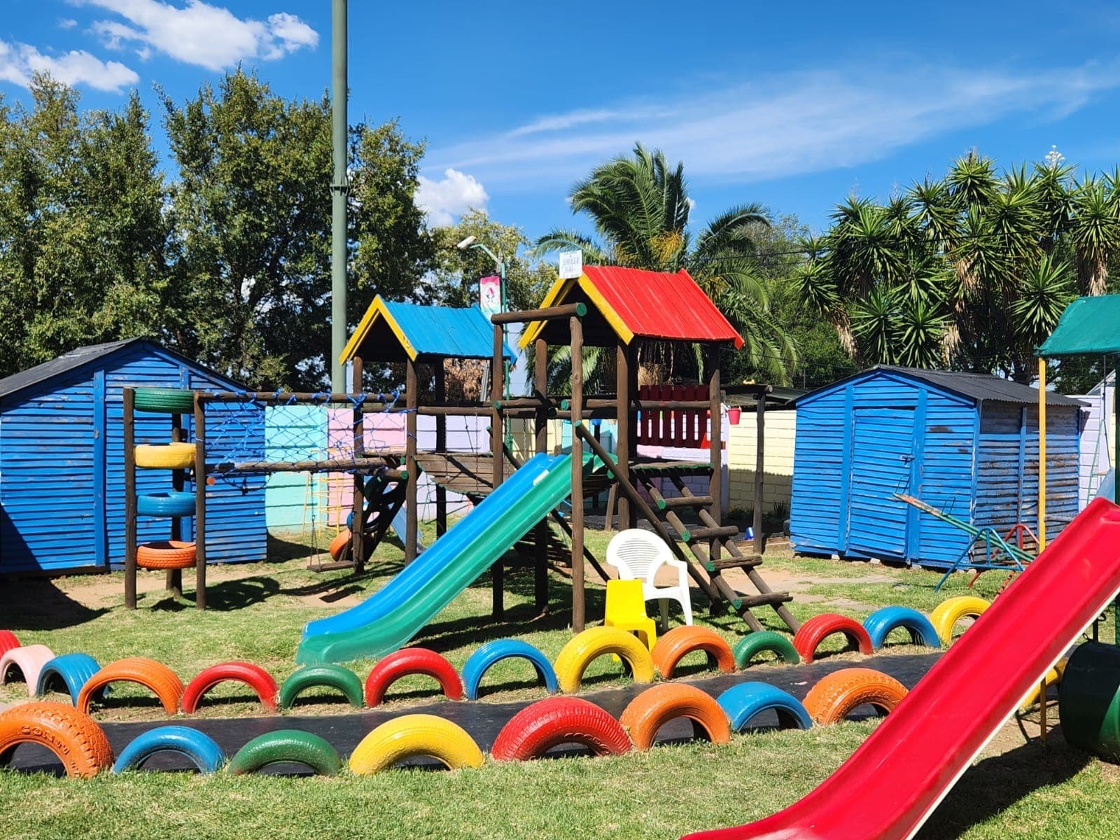 Tiny Town's playground with wooden climbing frames, slides and a path of painted tyres across the yard